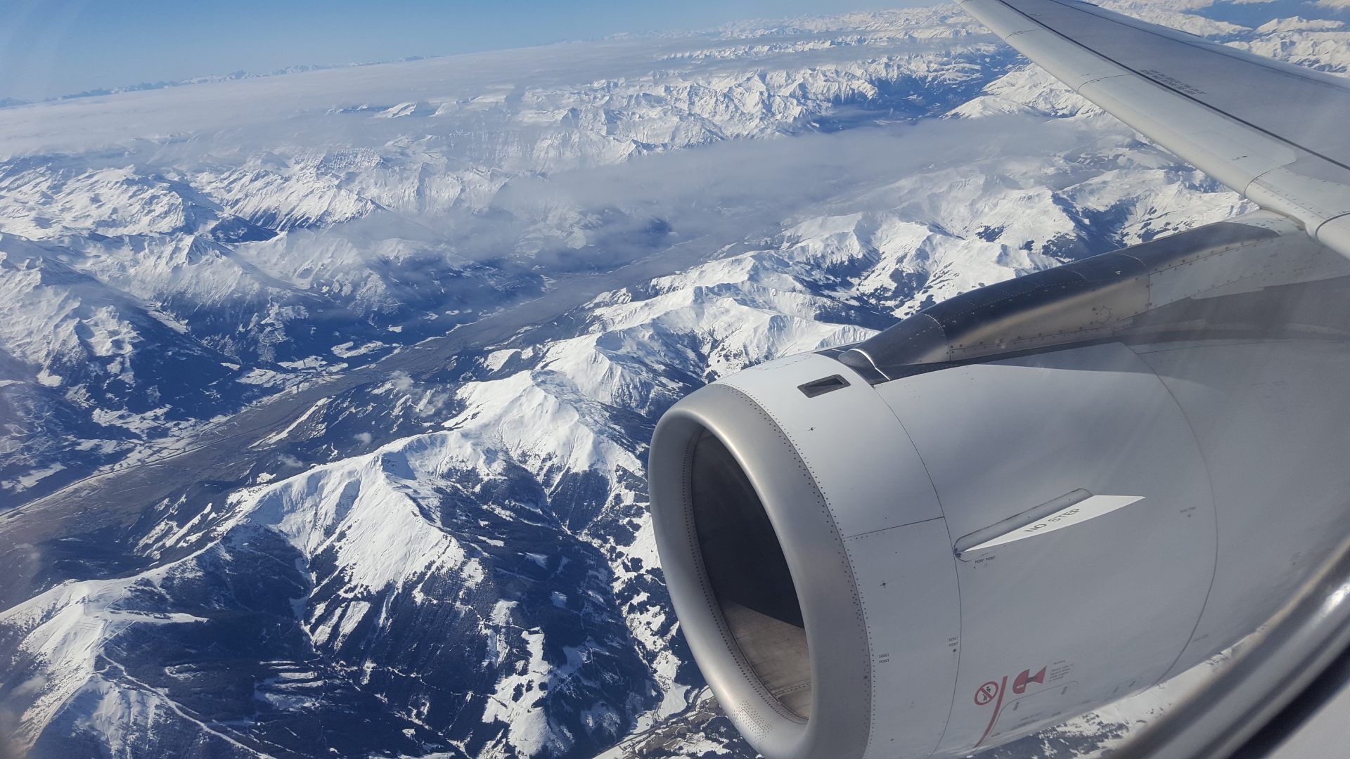 Ein Flugzeug fliegt über eine schneebedeckte Bergkette.