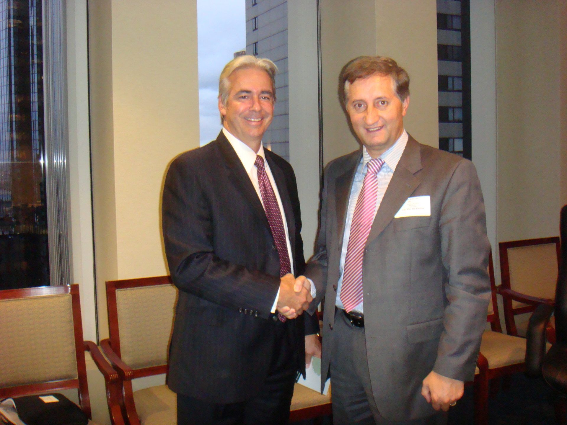 Ein Mann in Anzug und Krawatte schüttelt einem anderen Mann die Hand.