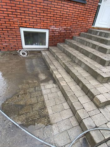 A man is using a high pressure washer to clean a patio.