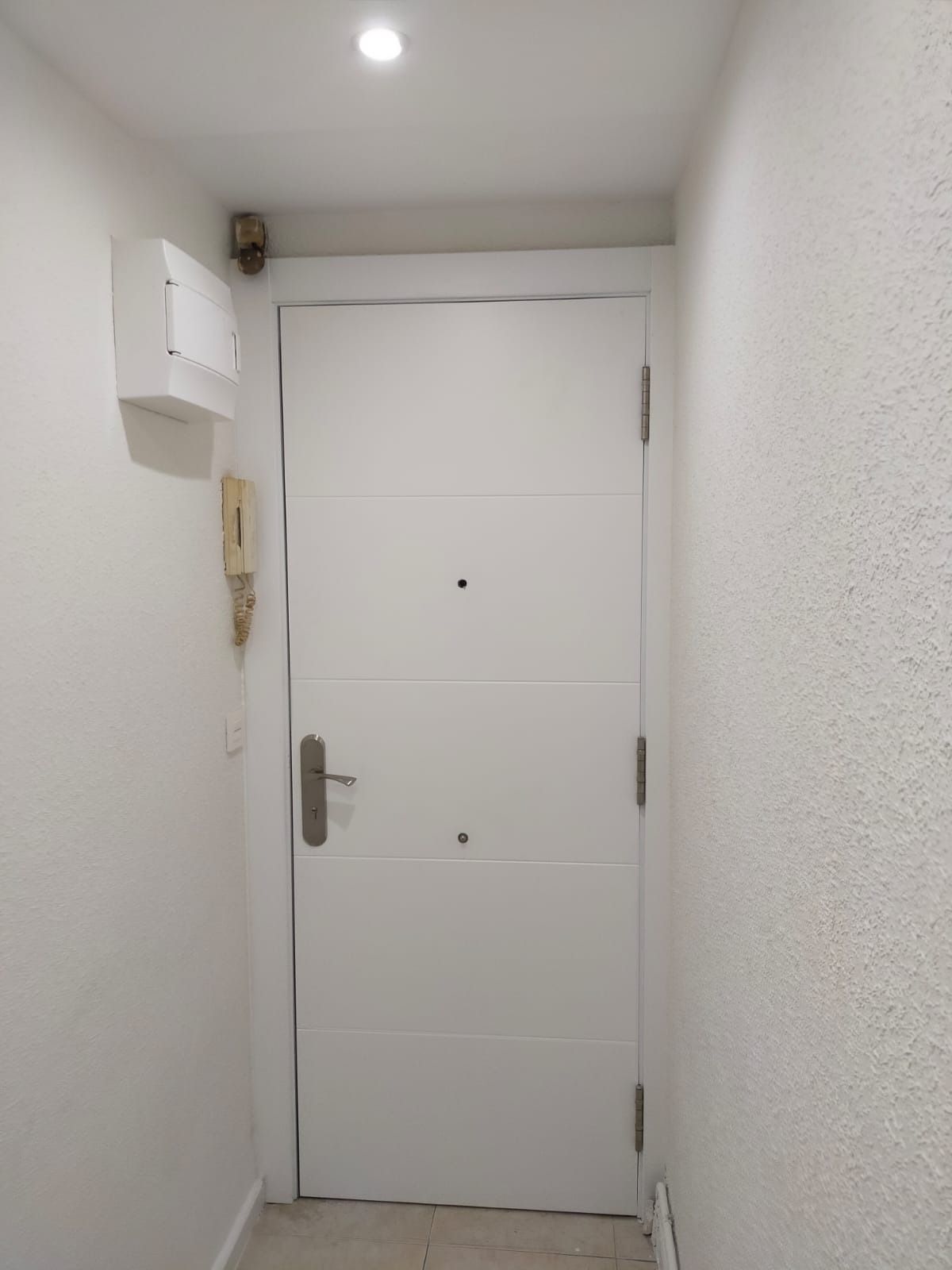 Una sencilla puerta interior blanca, centrada en un pasillo 