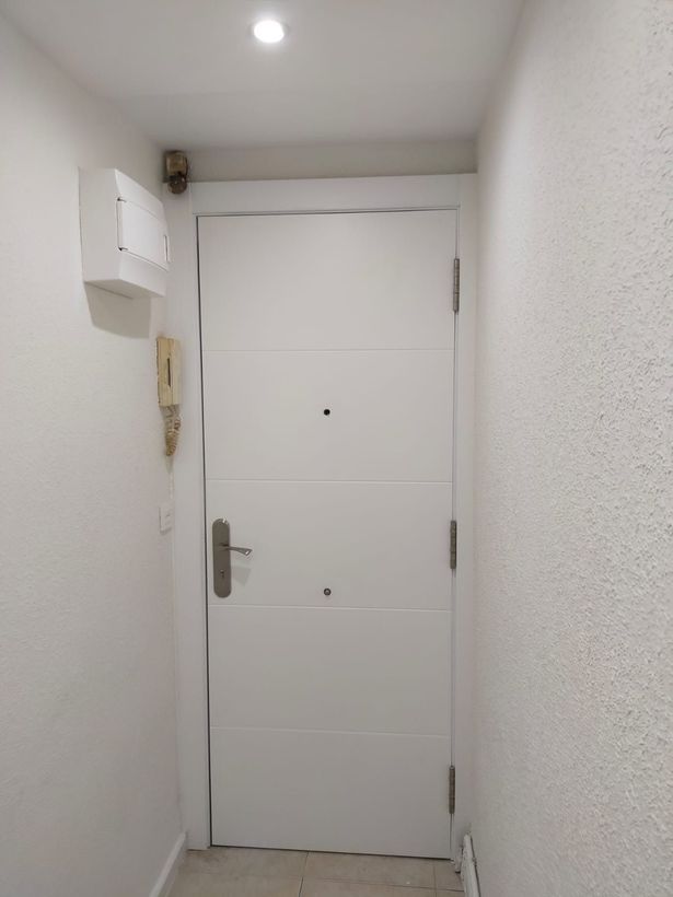 Una sencilla puerta interior blanca, centrada en un pasillo 