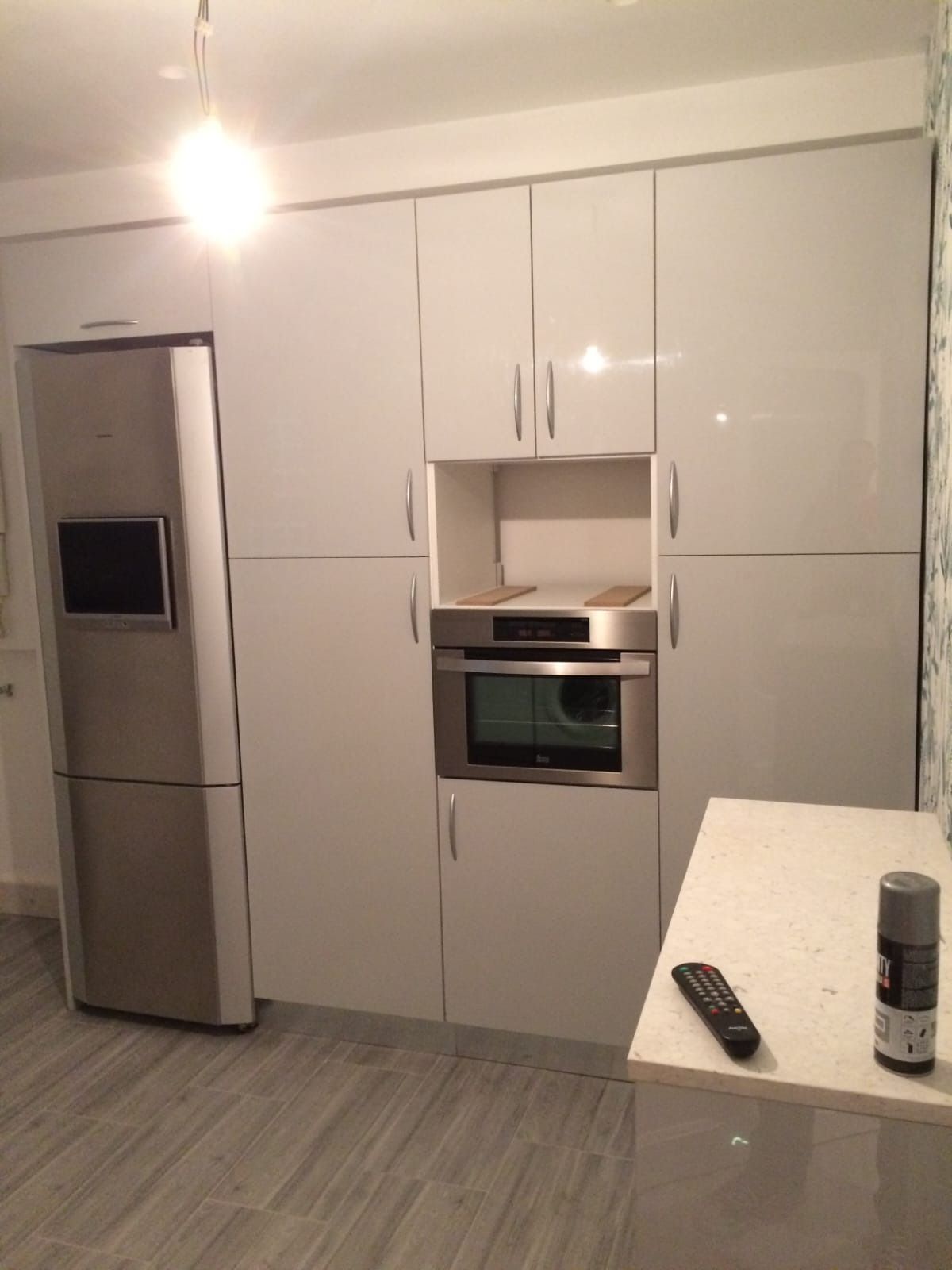 Vista de una cocina que muestra blancos con horno empotrado y encimera blanca.