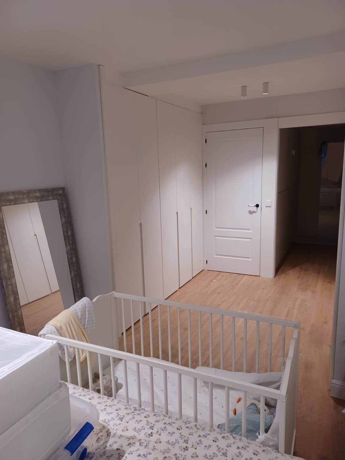 Una cuna blanca se encuentra en una habitación luminosa con 