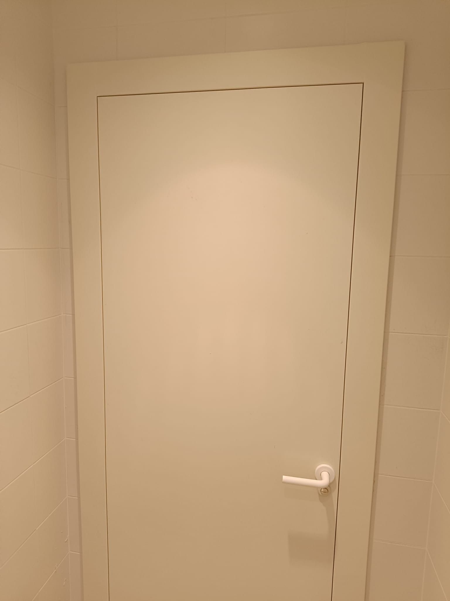 Una puerta interior blanca con manija blanca, enmarcada por 