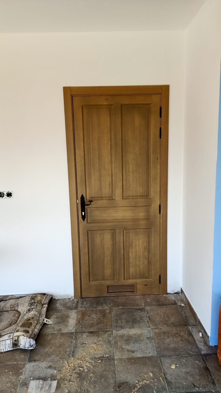 Una puerta interior de madera de cuatro paneles con manija negra