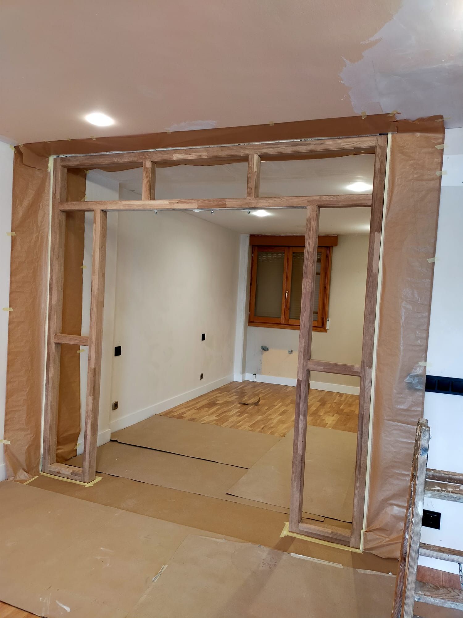 Un marco de madera en construcción entre dos habitaciones, con los bordes cubiertos con papel marrón.
