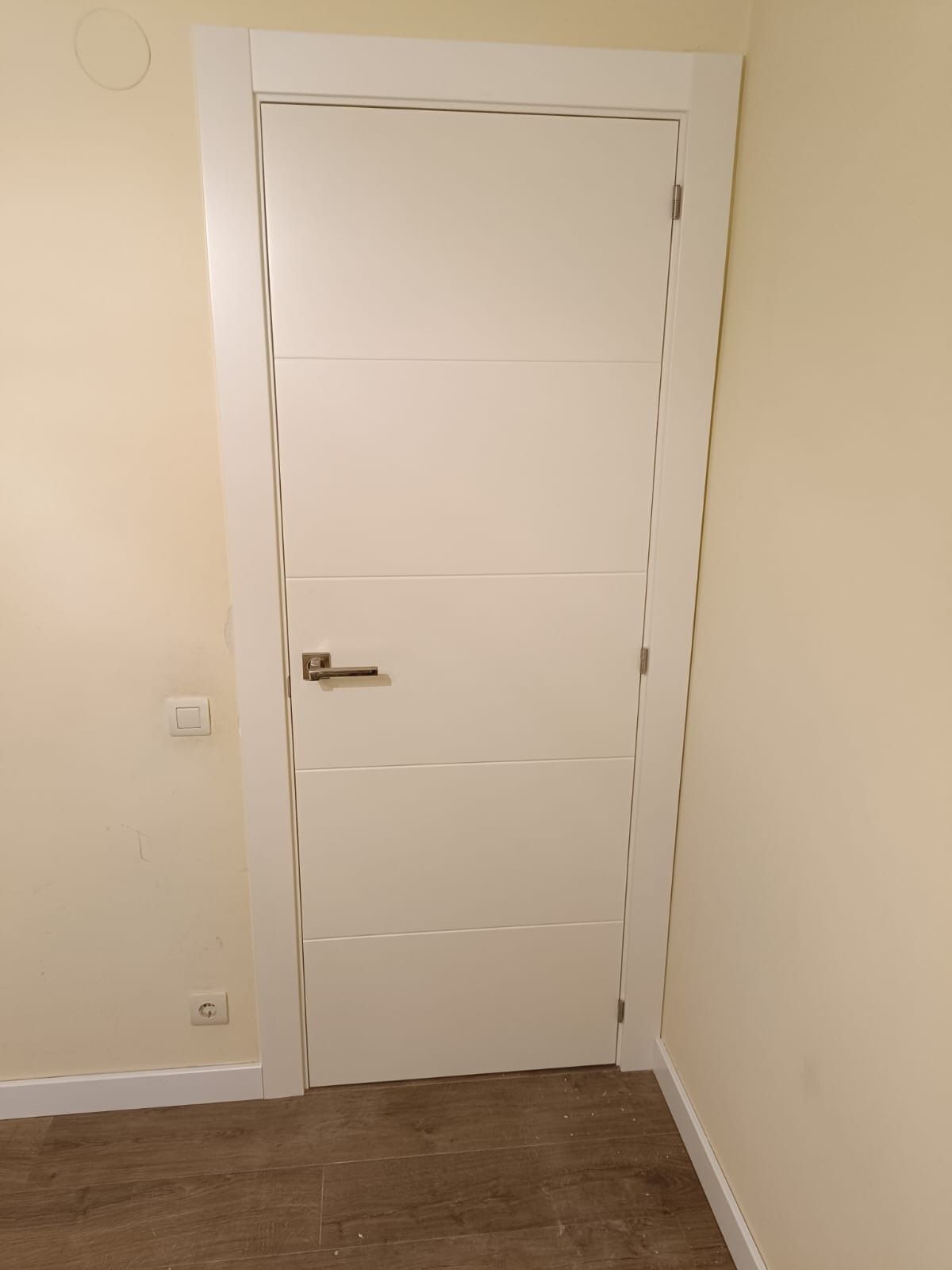 Una puerta interior blanca de cuatro paneles con tirador 