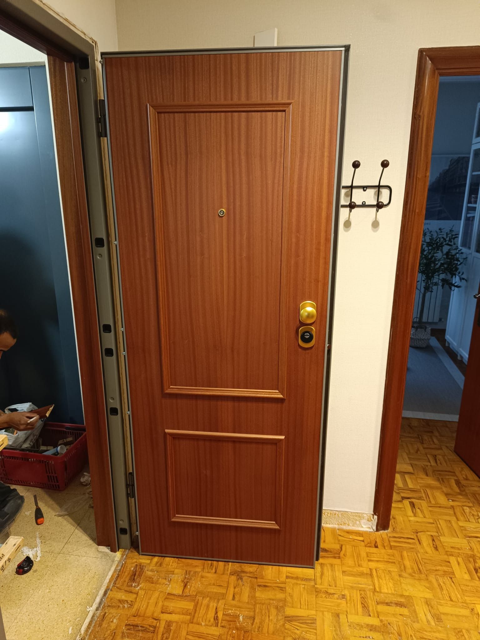 Una puerta interior con acabado de madera, pomo dorado y mirilla, situada en una habitación con suelo de parqué.