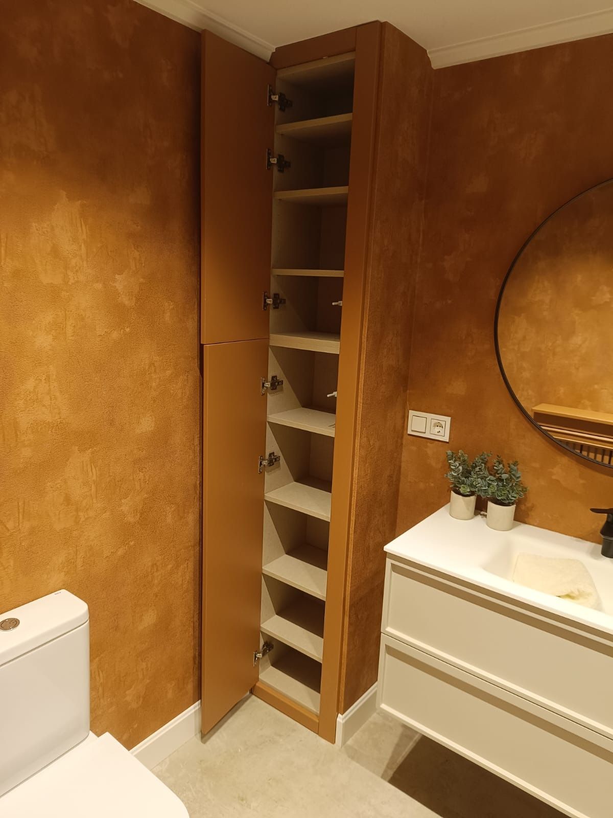 Un baño con paredes texturizadas de color naranja, un 