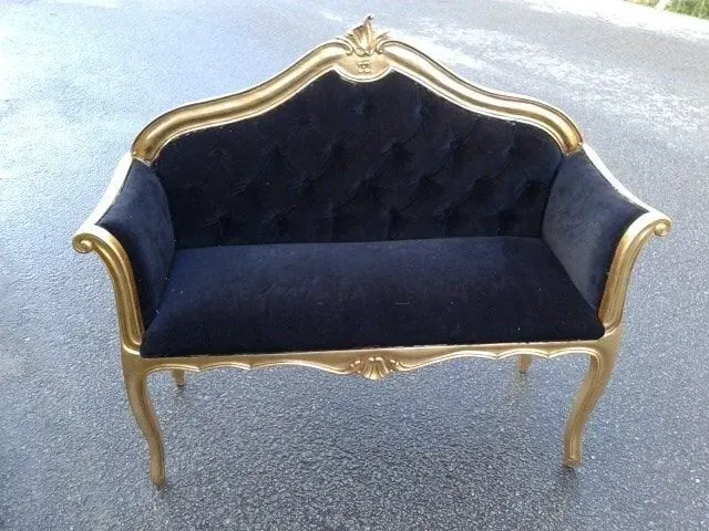 Um sofá preto e dourado está sentado no chão