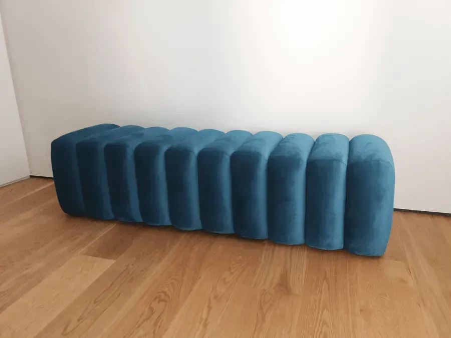 Um pufe azul está sobre um piso de madeira em uma sala.