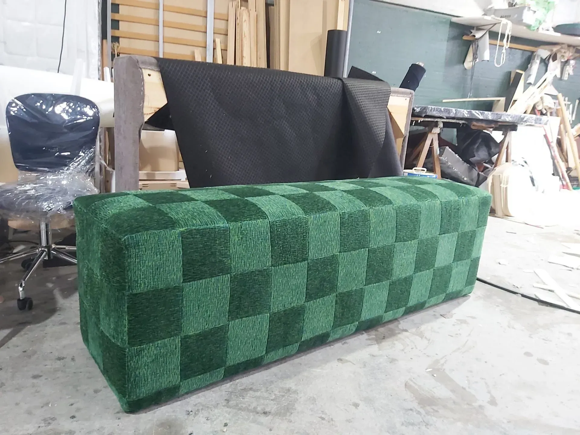 Um pufe xadrez verde está no chão de uma sala.