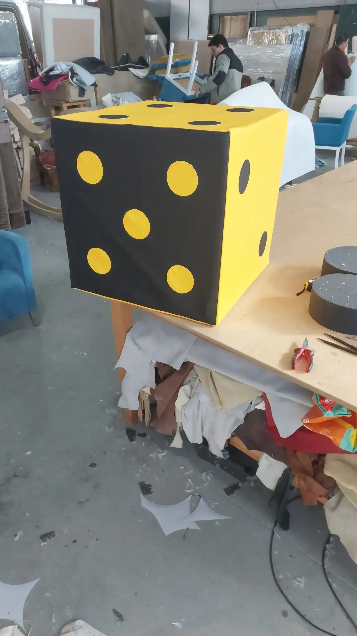Um dado amarelo e preto com pontos amarelos está sobre uma mesa.
