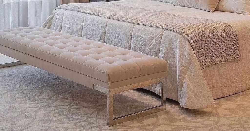 Um quarto com uma cama e um banco ao lado.