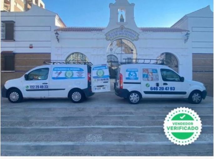 Dos camionetas están estacionadas frente a un edificio que dice verificado