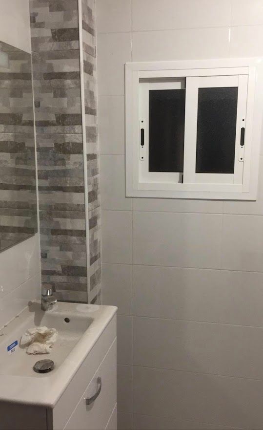 Un baño con lavabo, espejo y ventana.