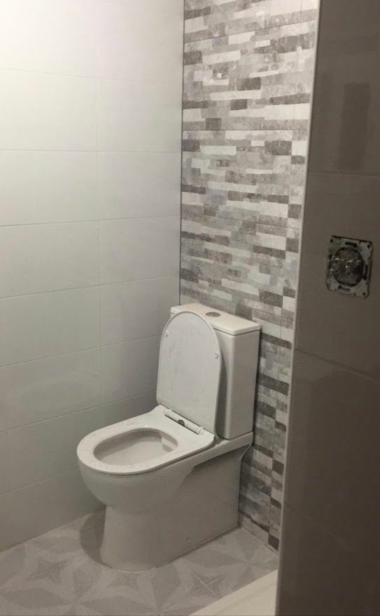 Un inodoro está sentado en un baño al lado de una pared de ladrillos.