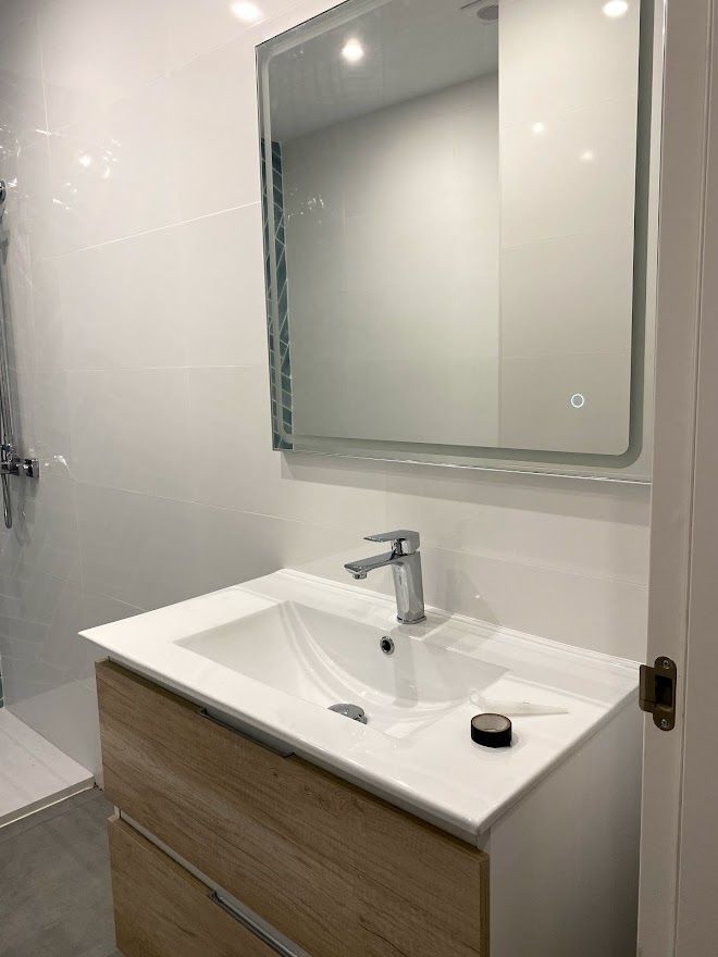 Un baño con lavabo, espejo y ducha.