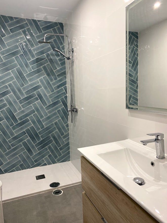 Un baño con lavabo, espejo y ducha.