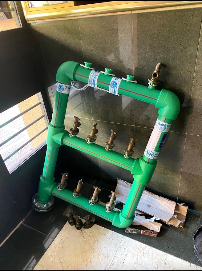 Una tubería verde con grifos conectados está tirada en el suelo de una habitación.