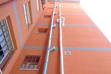 Un edificio con muchas ventanas y tuberías a los lados.