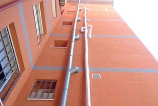 Un edificio con muchas ventanas y tuberías a los lados.