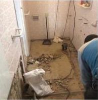 Un hombre está trabajando en el piso de un baño.