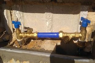 Un primer plano de un tubo de latón con una manguera azul unida a él.