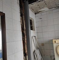 Un baño con azulejos blancos, una estufa y un espejo.