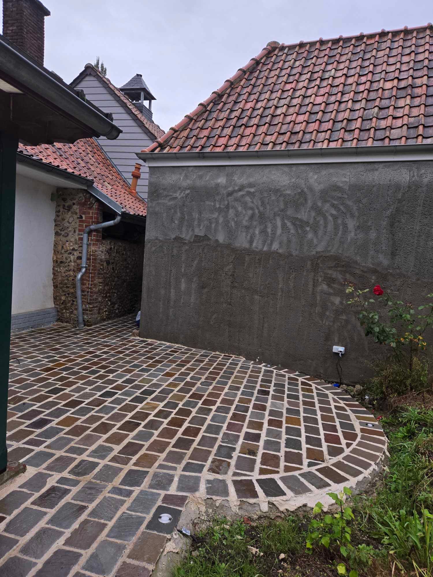 Une entrée de garage en cours d’aménagement avec du gravier compacté et des bordures bétonnées