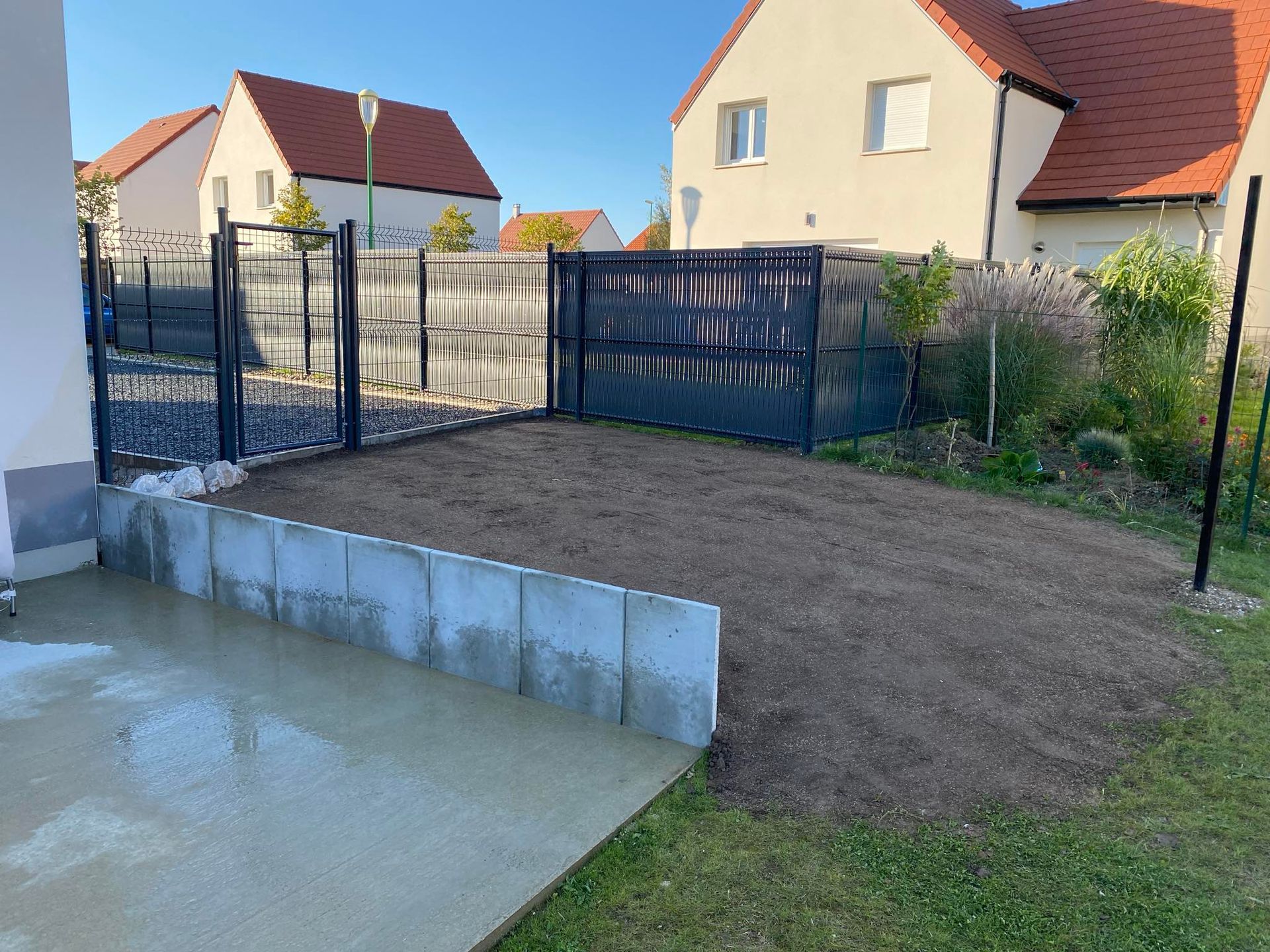 Une entrée de garage en cours d’aménagement avec du gravier compacté et des bordures bétonnées