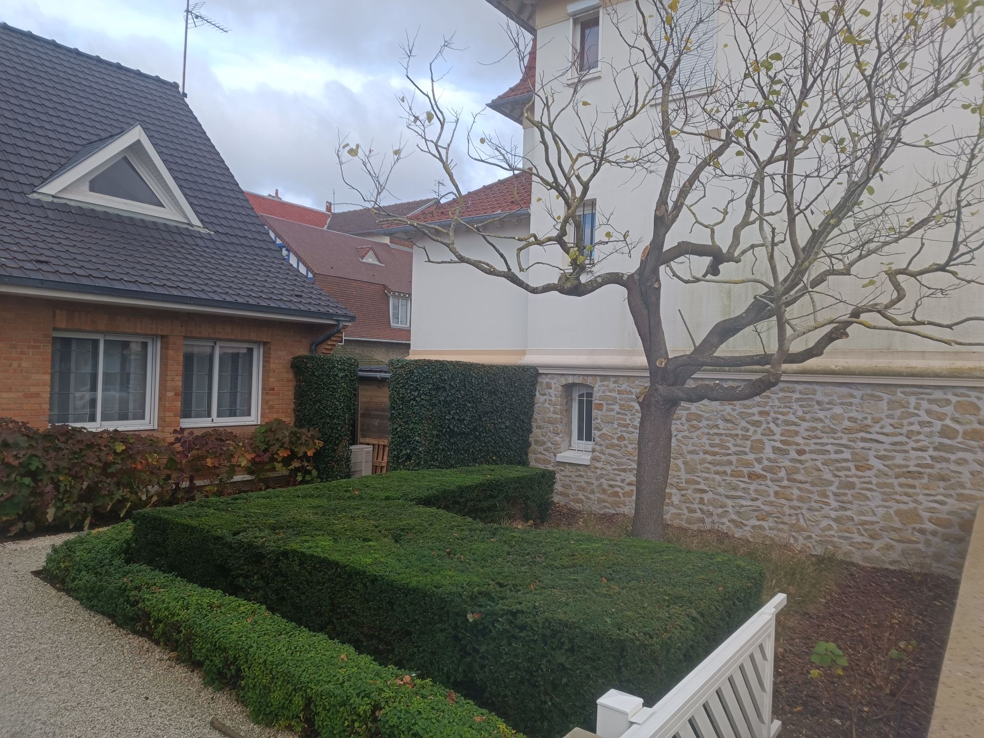 Un coin aménagé avec des graviers, un banc et une table sous un arbre
