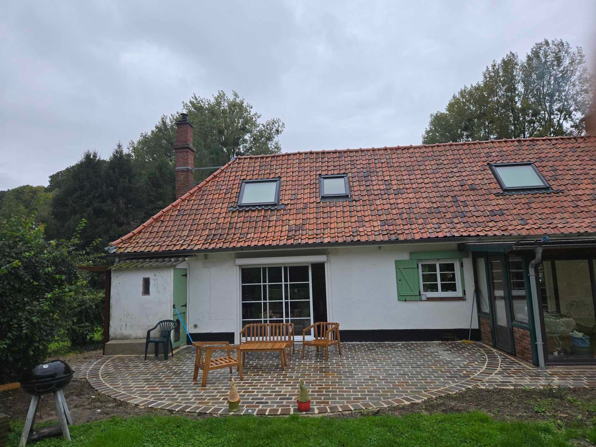 Une maison de style traditionnel avec une terrasse en bois et un espace vert en arrière-plan