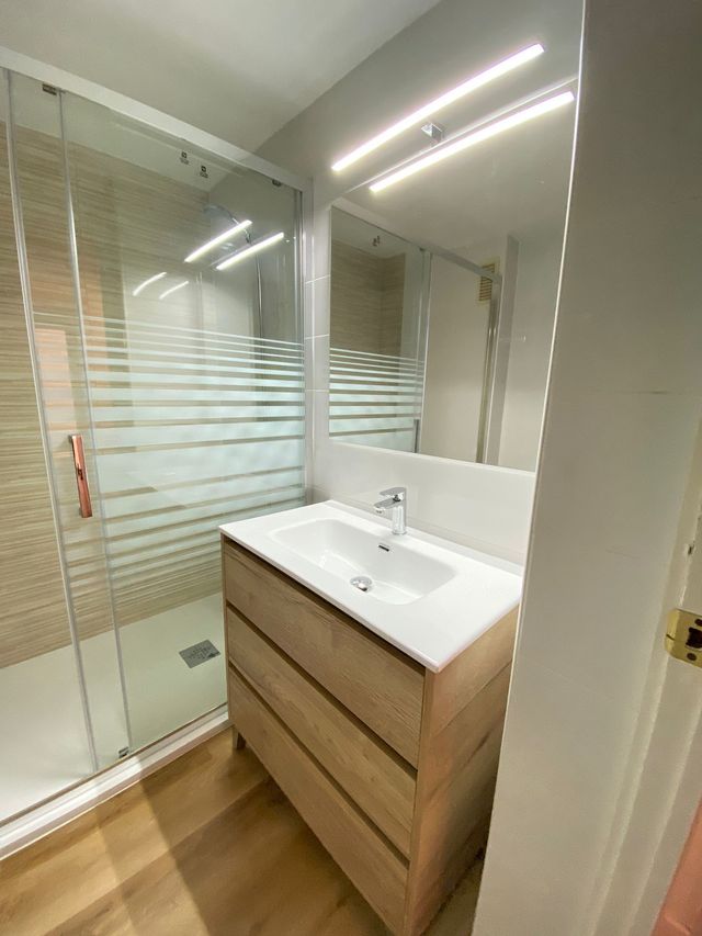 Un baño con lavabo, espejo y cabina de ducha.