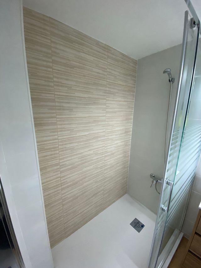 Un baño con ducha a ras de suelo y puerta de cristal.