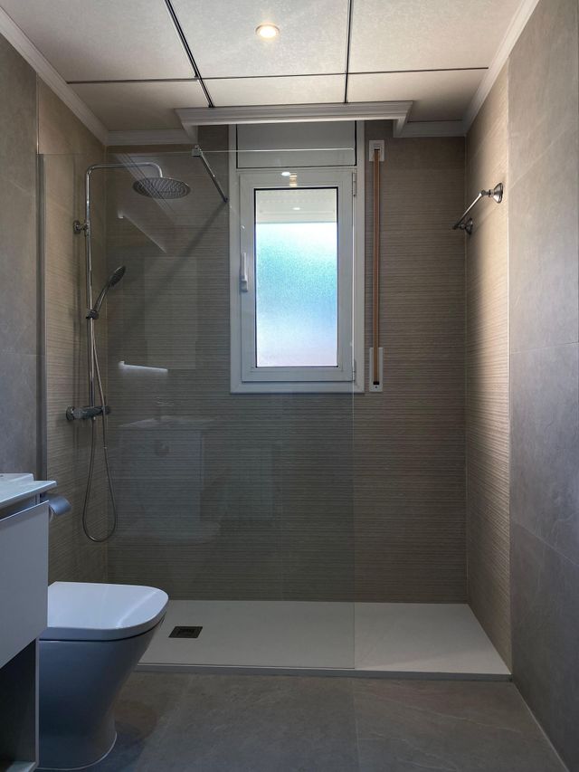 Un baño con inodoro y ducha a ras de suelo.
