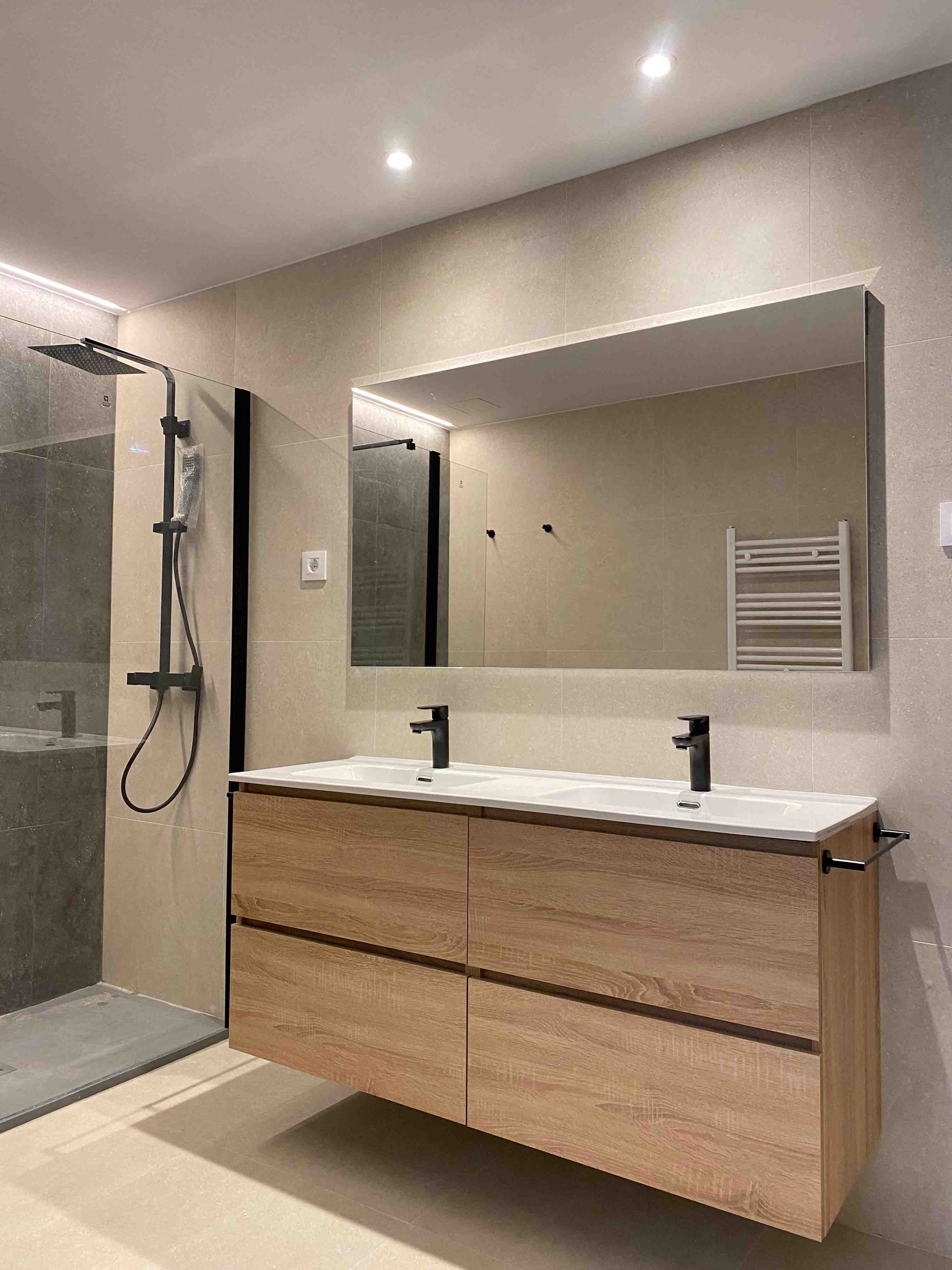 Un baño con dos lavabos, una ducha y un espejo.