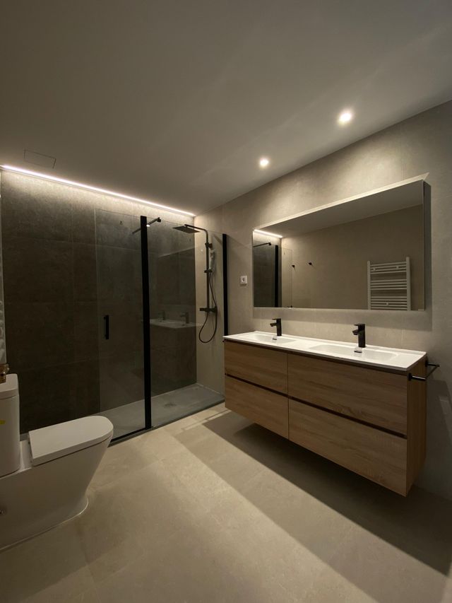 Un baño con inodoro, lavabo, espejo y ducha.