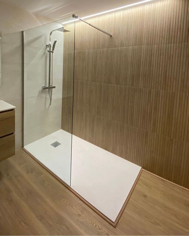 Un baño con ducha a ras de suelo y suelo de madera.