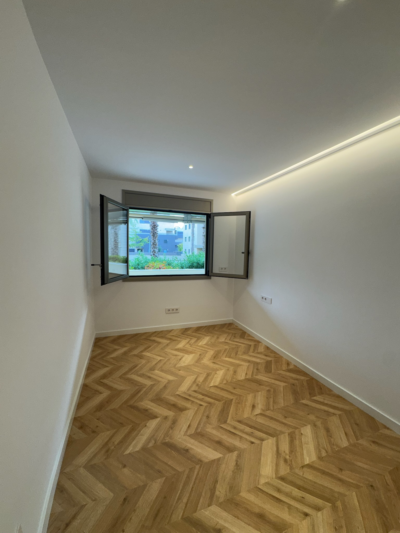 Una habitación vacía con suelo de madera y una ventana.