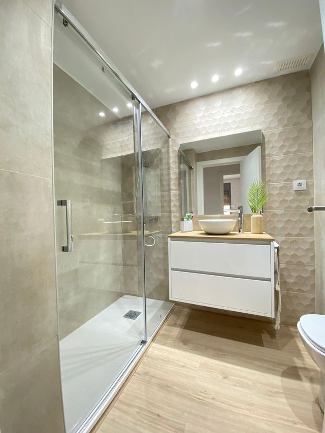 Un baño con ducha, lavabo, espejo e inodoro.