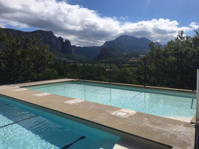 Piscine avec vue sur une chaîne de montagnes sous un ciel nuageux.