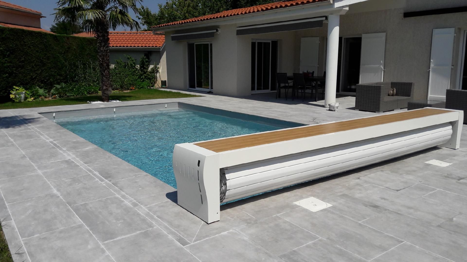 Piscine avec chaises longues près d'un mur de pierre par une journée ensoleillée.