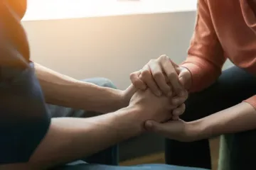 Manos unidas en comodidad; luz cálida.