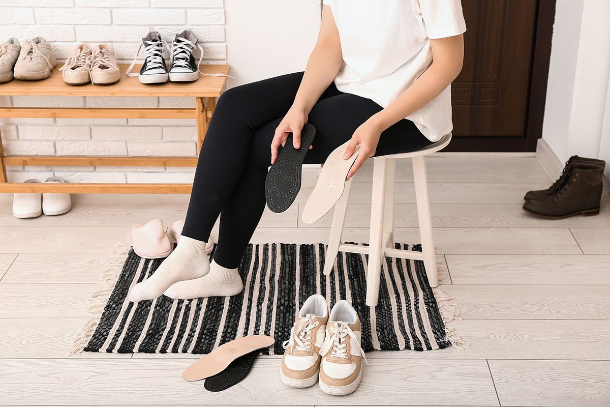 Femme assise sur un tabouret qui met des semelles orthopédiques dans ses chaussures