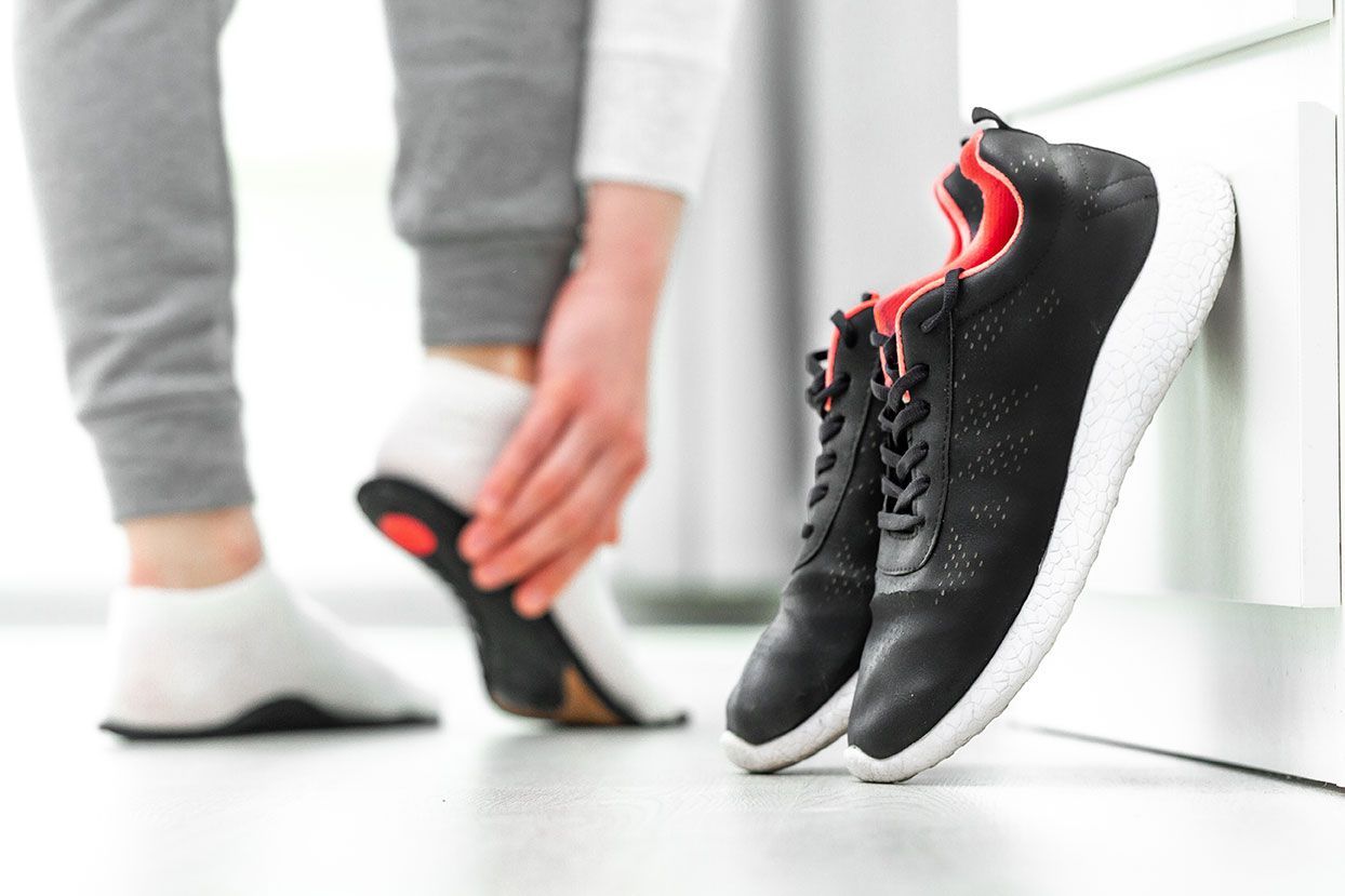 Femme qui essage des semelles orthopédiques dans ses chaussures de sport