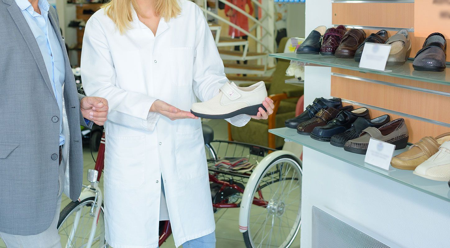 Femme qui montre des chaussures orthopédiques à un homme dans un centre médical
