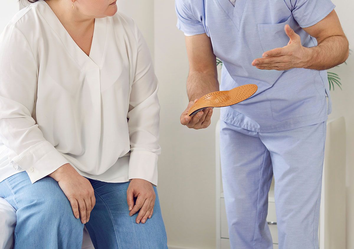 Praticien qui présente une semelle orthopédique à une patiente