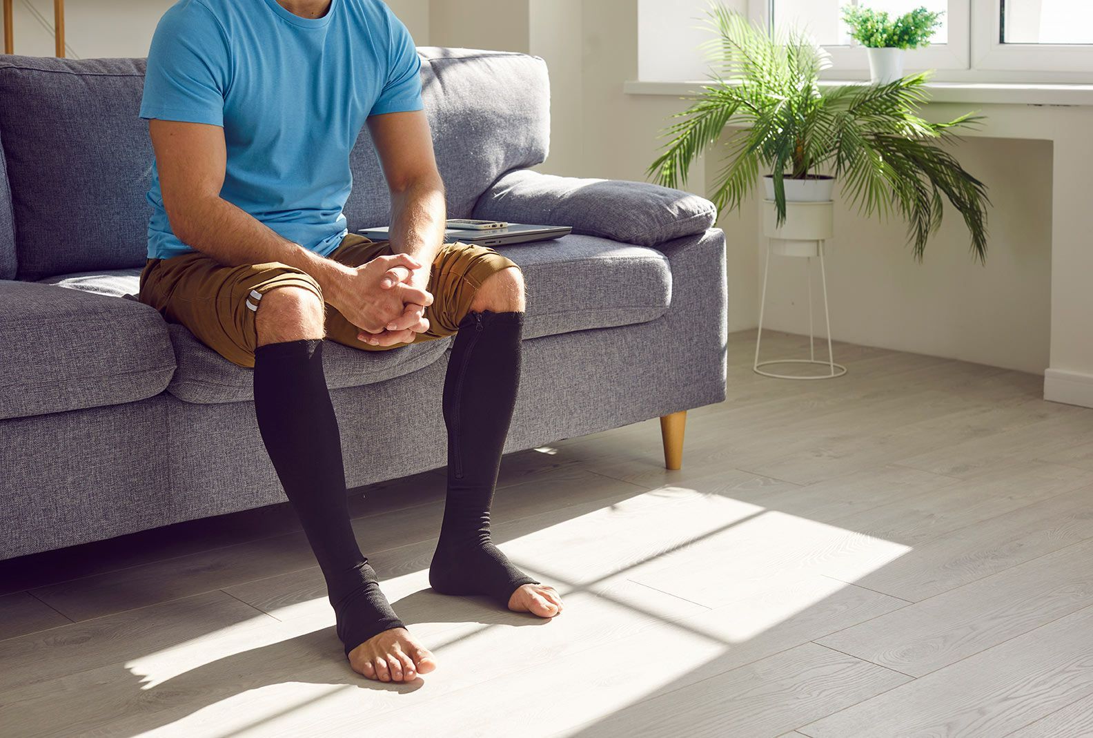 Homme assis sur son canapé avec des bas de contention noirs