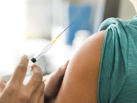 Seringue administrant une injection dans le haut du bras d'une personne en milieu clinique.